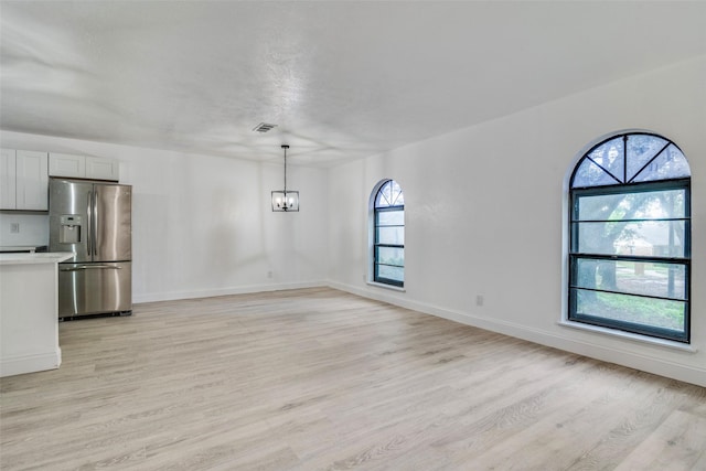 6401 Gate Ridge Cir, Garland, TX 75043 - unfurnished dining area featuring a healthy amount of sunlight, a notable chandelier, light wood finished floors, and visible vents
