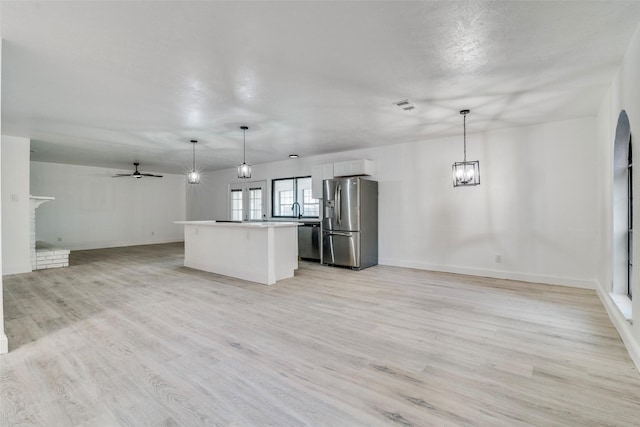 6401 Gate Ridge Cir, Garland, TX 75043 - kitchen with a kitchen island, ceiling fan with notable chandelier, open floor plan, light wood-style floors, and stainless steel appliances
