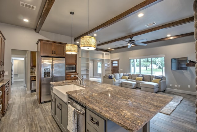 kitchen featuring appliances with stainless steel finishes, a sink, beam ceiling, wood finished floors, and ceiling fan