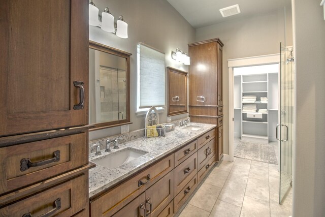 bathroom with tile patterned flooring, a shower stall, and double vanity
