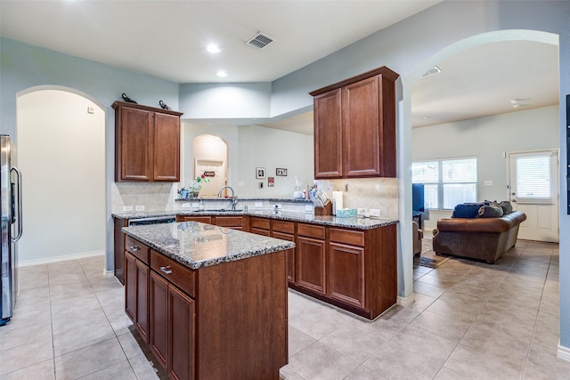 9204 Lockhart Dr, Arlington, TX 76002 - kitchen with arched walkways, dark stone counters, backsplash, and recessed lighting