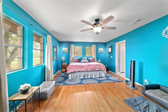 bedroom featuring baseboards, multiple windows, wood finished floors, and visible vents