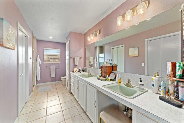 bathroom with tile patterned flooring, a sink, a textured ceiling, and toilet