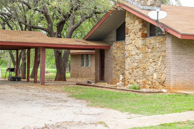 view of property exterior featuring roof with shingles, brick siding, and stone siding