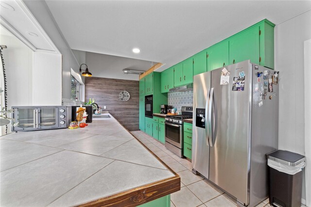 kitchen featuring appliances with stainless steel finishes, tasteful backsplash, a sink, light tile patterned floors, and a toaster