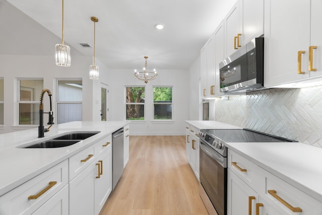 kitchen with decorative backsplash, appliances with stainless steel finishes, a sink, light countertops, and light wood-style floors