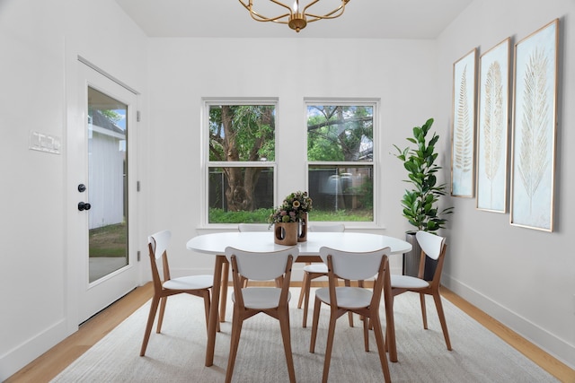 dining space with a chandelier, plenty of natural light, and light wood finished floors