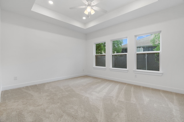 unfurnished room with baseboards, recessed lighting, a tray ceiling, and light colored carpet