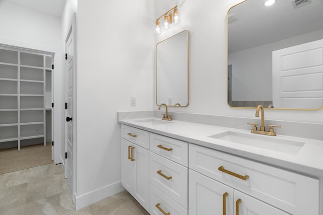 bathroom with a sink, baseboards, double vanity, and visible vents