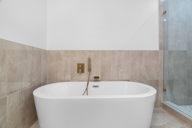 full bath with tiled shower, tile walls, and a soaking tub
