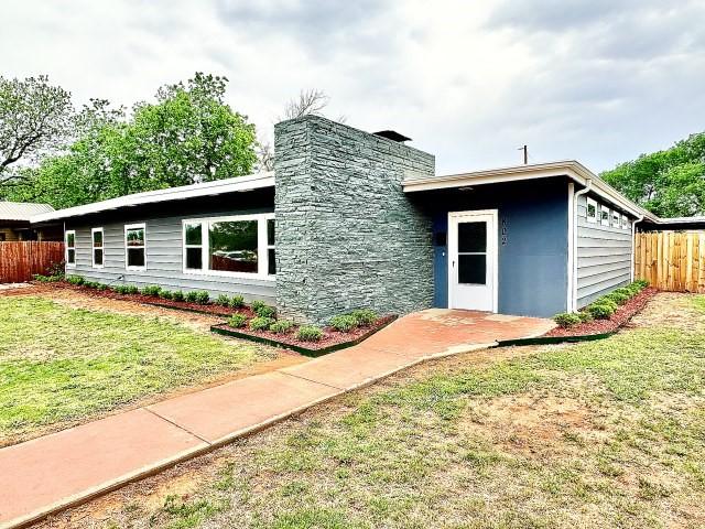 view of front facade with fence, a chimney, and a front lawn