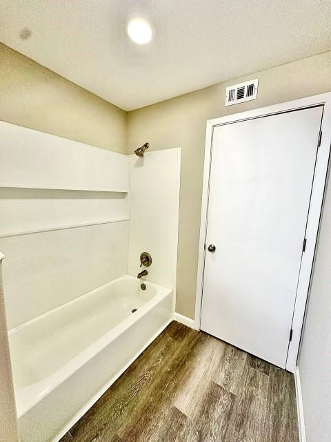 full bath with visible vents, tub / shower combination, and wood finished floors