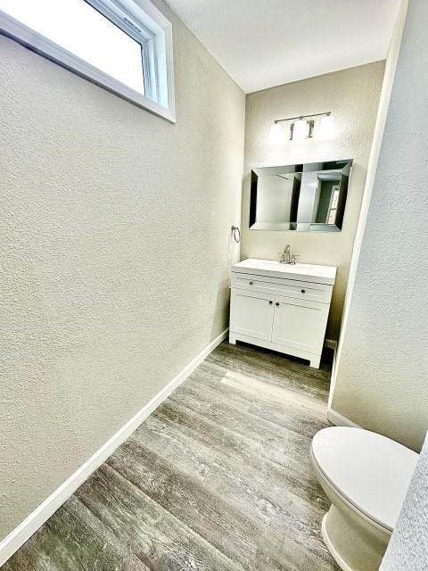 bathroom featuring a textured wall, baseboards, and wood finished floors