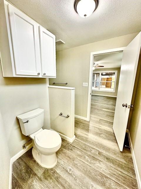 bathroom featuring baseboards, a textured ceiling, and wood finished floors