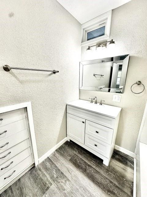 bathroom with vanity, baseboards, a textured wall, and wood finished floors