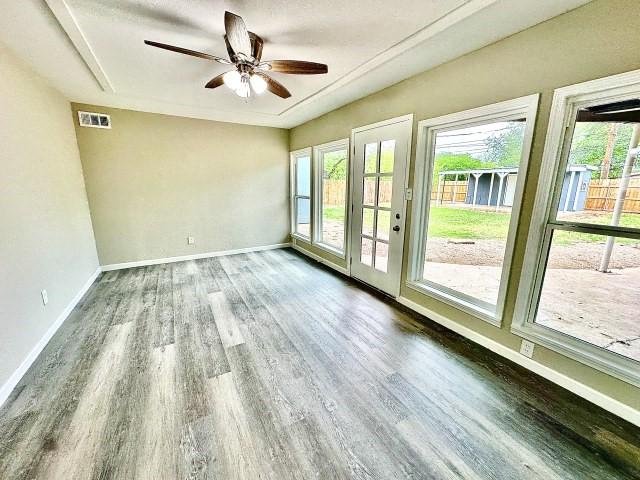 unfurnished room featuring ceiling fan, baseboards, visible vents, and wood finished floors