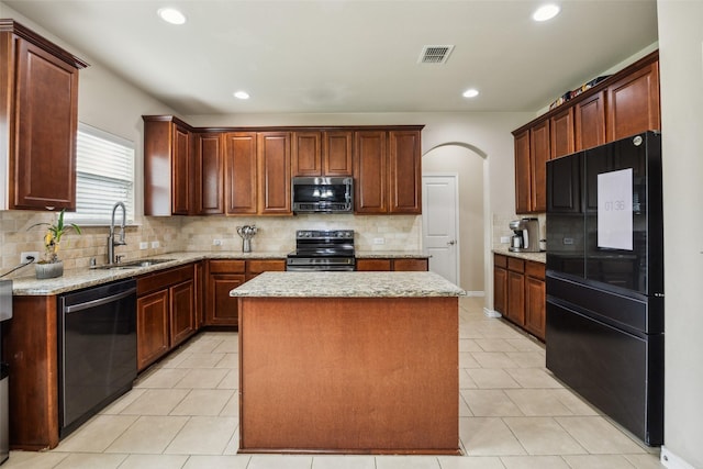 kitchen with visible vents, a kitchen island, a sink, backsplash, and black appliances