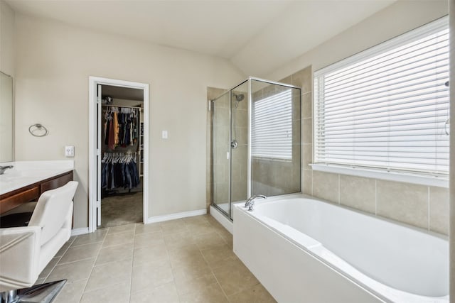 bathroom featuring vanity, a walk in closet, a stall shower, and a garden tub
