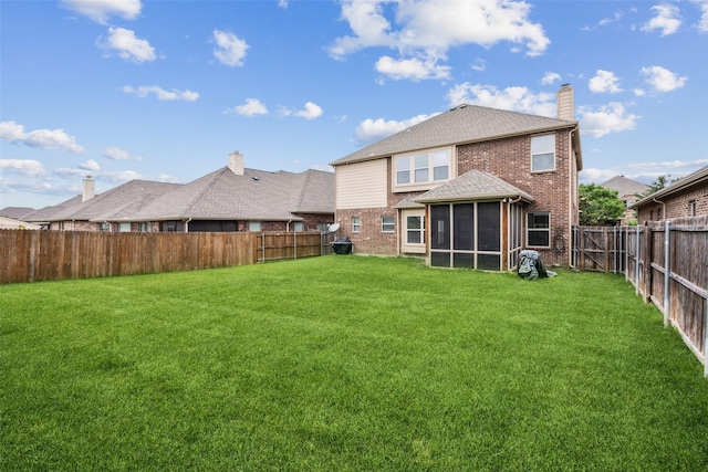 back of property featuring a lawn, brick siding, a fenced backyard, and a sunroom
