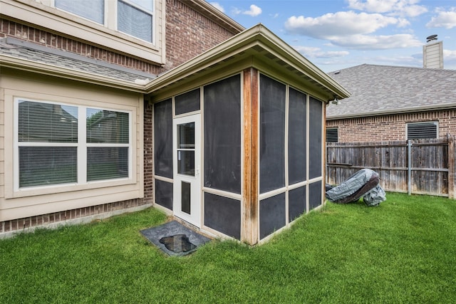 view of outbuilding featuring fence and a sunroom