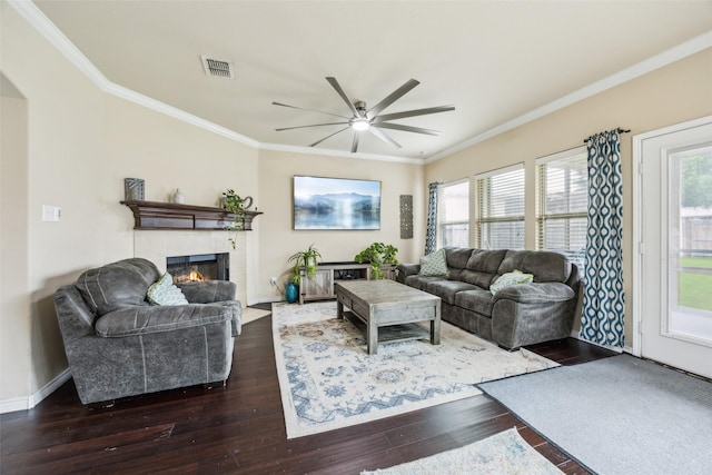 living area featuring a healthy amount of sunlight, a ceiling fan, visible vents, a fireplace, and dark wood-type flooring