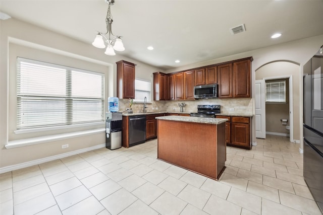 kitchen featuring a sink, appliances with stainless steel finishes, decorative backsplash, and a chandelier