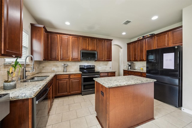 kitchen with visible vents, a kitchen island, light stone countertops, a sink, and stainless steel appliances