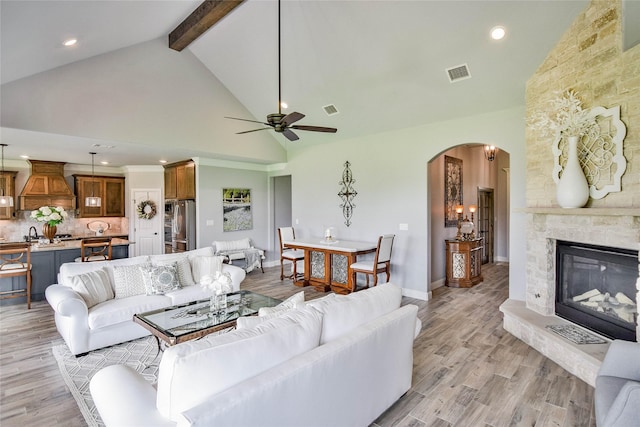 living room featuring beam ceiling, arched walkways, high vaulted ceiling, a ceiling fan, and visible vents