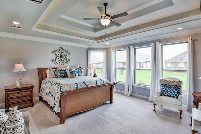 bedroom with light colored carpet, a tray ceiling, visible vents, and multiple windows