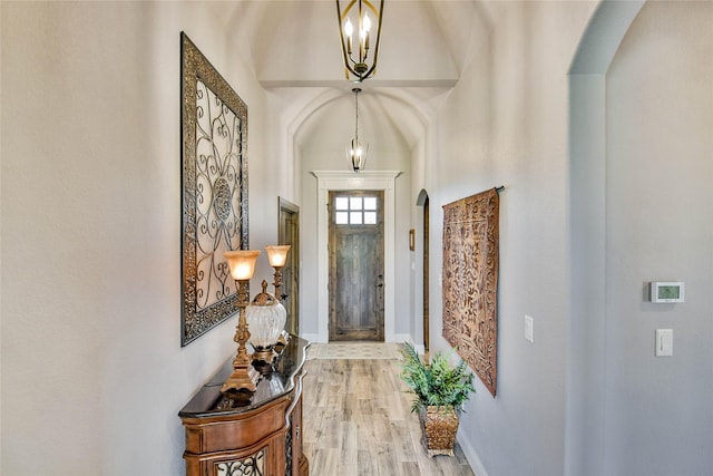 foyer featuring baseboards, arched walkways, and wood finished floors