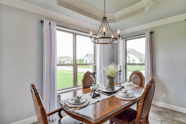 dining area with plenty of natural light, light wood finished floors, a tray ceiling, and a chandelier