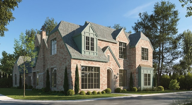 tudor house featuring brick siding, a chimney, and a shingled roof