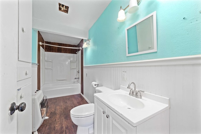 bathroom featuring wainscoting, bathtub / shower combination, vanity, toilet, and wood finished floors