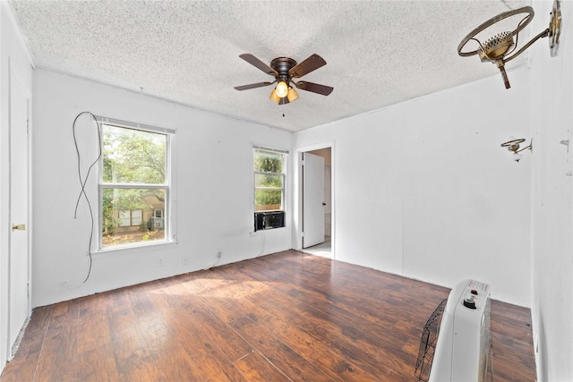 empty room featuring a ceiling fan, a textured ceiling, wood finished floors, and cooling unit