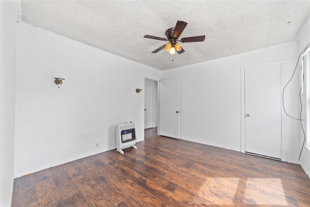 empty room featuring heating unit, ceiling fan, a textured ceiling, and wood finished floors