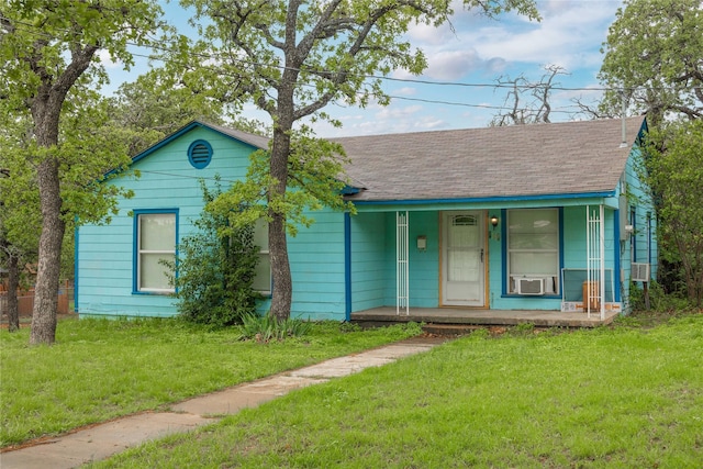 single story home with a porch, a shingled roof, and a front yard