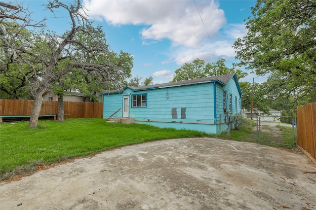 back of house featuring a lawn, fence, and entry steps