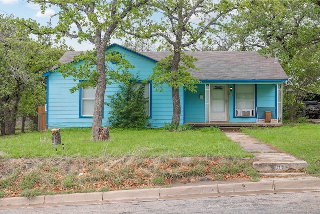 view of front facade with roof with shingles, covered porch, and a front yard