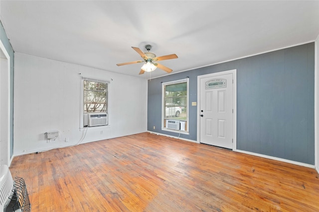 empty room with wood-type flooring, ceiling fan, a wealth of natural light, and cooling unit