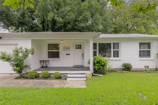 ranch-style home with covered porch, an attached garage, a front lawn, and brick siding