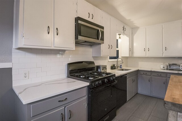 kitchen with gray cabinets, backsplash, a sink, a toaster, and black appliances