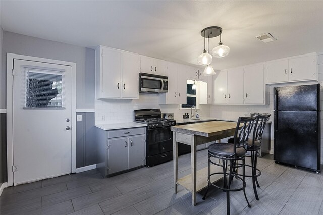 kitchen featuring visible vents, decorative backsplash, white cabinetry, and black appliances