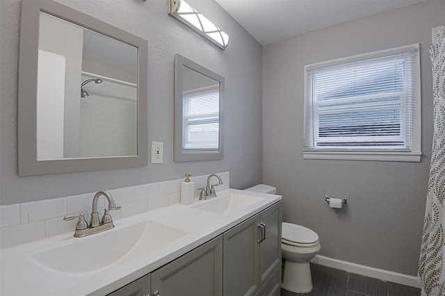 full bathroom with a sink, baseboards, toilet, and double vanity