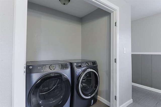laundry area featuring baseboards, washing machine and dryer, and wood finished floors