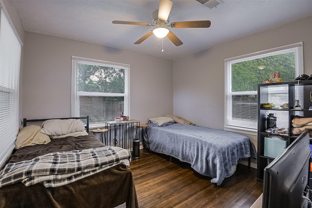 bedroom with a ceiling fan, wood finished floors, and visible vents