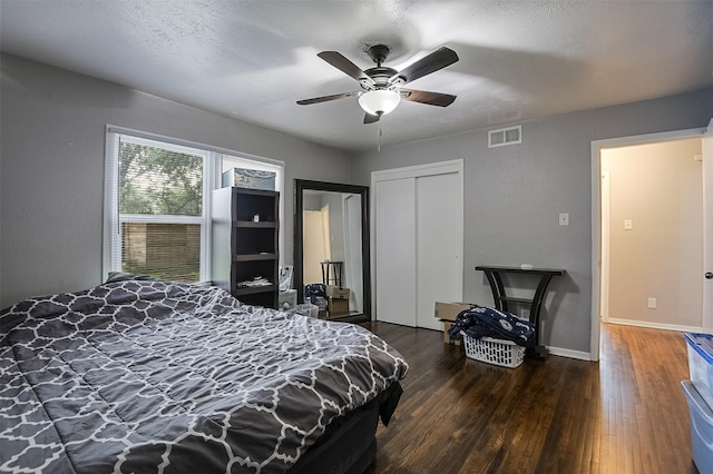 bedroom with visible vents, a closet, wood finished floors, baseboards, and ceiling fan