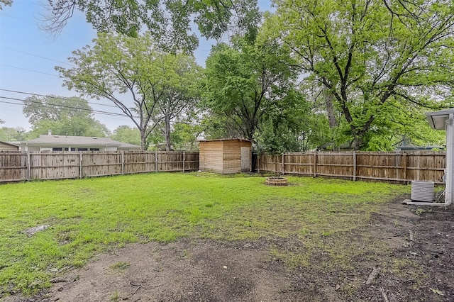 view of yard with an outdoor structure, a fenced backyard, a fire pit, and a shed