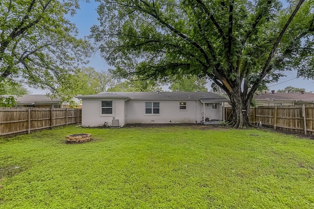 back of house with a lawn, a fenced backyard, an outdoor fire pit, and central air condition unit