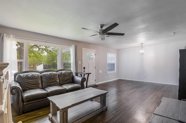 living room featuring baseboards, ceiling fan with notable chandelier, dark wood-style flooring, and visible vents