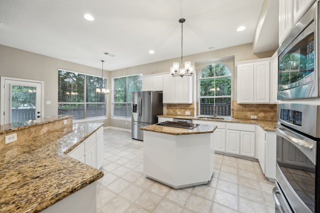 kitchen with stainless steel appliances, a notable chandelier, a healthy amount of sunlight, and a center island